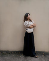 Full-length view of a customer styling the cream Moving Through bag with a neutral blouse and dark skirt for a minimalist everyday look.