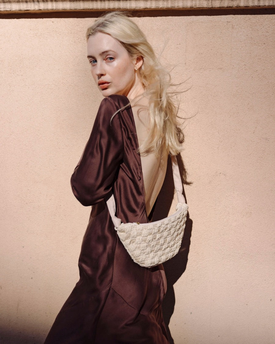 Back view of a model wearing the cream Moving Through bag, illustrating the 43cm shoulder strap drop and comfortable crossbody wear.