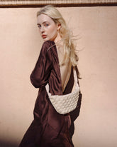 Back view of a model wearing the cream Moving Through bag, illustrating the 43cm shoulder strap drop and comfortable crossbody wear.