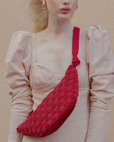 Detailed shot of the red Moving Through bag worn across the body, highlighting the tactile intricacy of the hand-woven glass beading