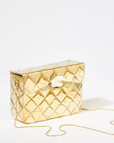 Three-quarter studio view of the gold Our Longing metal bag featuring a hand-beaten quilted texture and sculptural shell clasp.