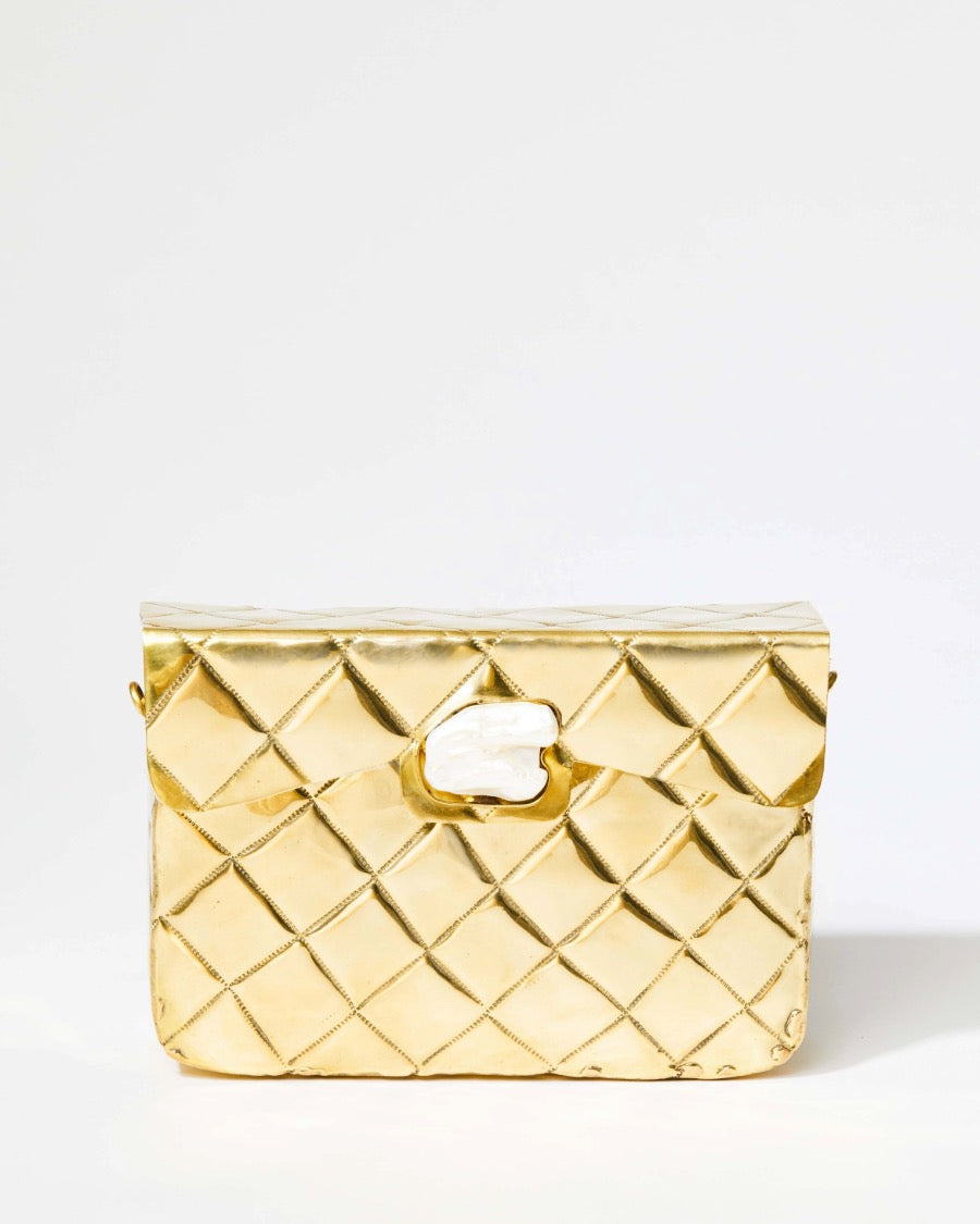 Straight-on studio view of the gold Our Longing bag highlighting the organic shell-shaped clasp and individually shaped metalwork.