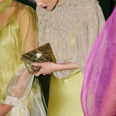 Candid lifestyle view of the gold metal bag paired with an elegant silk dress, perfect for weddings and special celebrations