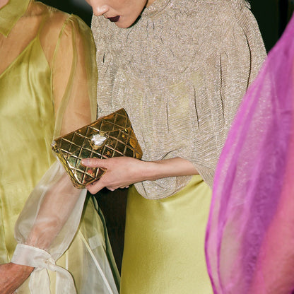 Candid lifestyle view of the gold metal bag paired with an elegant silk dress, perfect for weddings and special celebrations