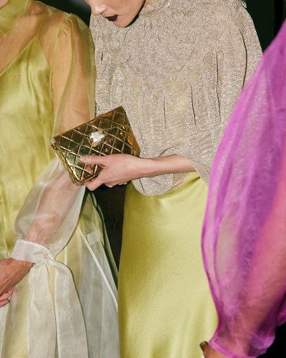 Candid lifestyle view of the gold metal bag paired with an elegant silk dress, perfect for weddings and special celebrations