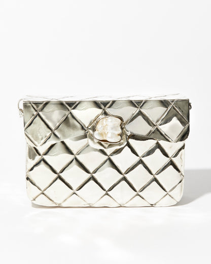 Front studio view of the silver Our Longing metal bag featuring a hand-beaten quilted texture and a signature shell-shaped clasp.