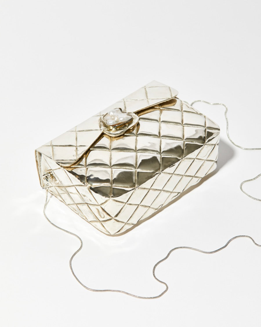 High-angle view of the silver metal bag showing the intricate individually shaped shell clasp and the high-shine quilted metal finish.