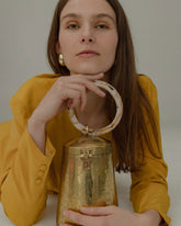 Model leaning on a surface holding the Perception of Time bag, demonstrating its 20cm height and sophisticated handheld style.