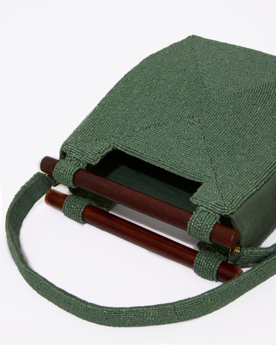 High-angle studio shot looking into the jade green beaded bag, emphasizing the clean architectural lines and wooden handle attachment.