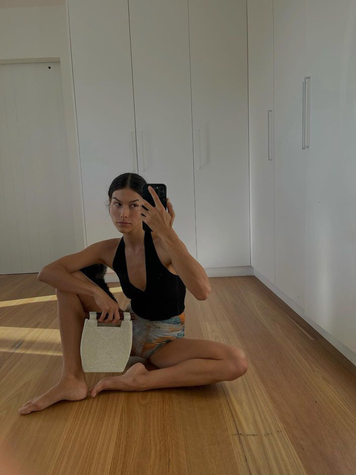 A UGC selfie of a model holding the Reach for Words bag by its wooden handles to demonstrate scale and handheld styling.