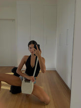 Candid lifestyle shot of the white beaded bag held in hand, highlighting its transition from a crossbody to a statement top-handle bag.