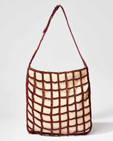 Front studio view of the Returning Form tote bag featuring a burgundy beaded grid design over a natural cream base.