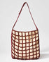 Front studio view of the Returning Form tote bag featuring a burgundy beaded grid design over a natural cream base.