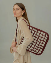Model wearing a tan blouse styling the Returning Form beaded tote over her shoulder, demonstrating its functional yet elevated look.
