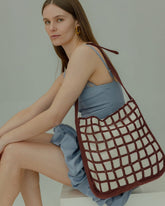 Model seated in a blue dress with the Returning Form tote, emphasising its versatile design for both professional and casual occasions.