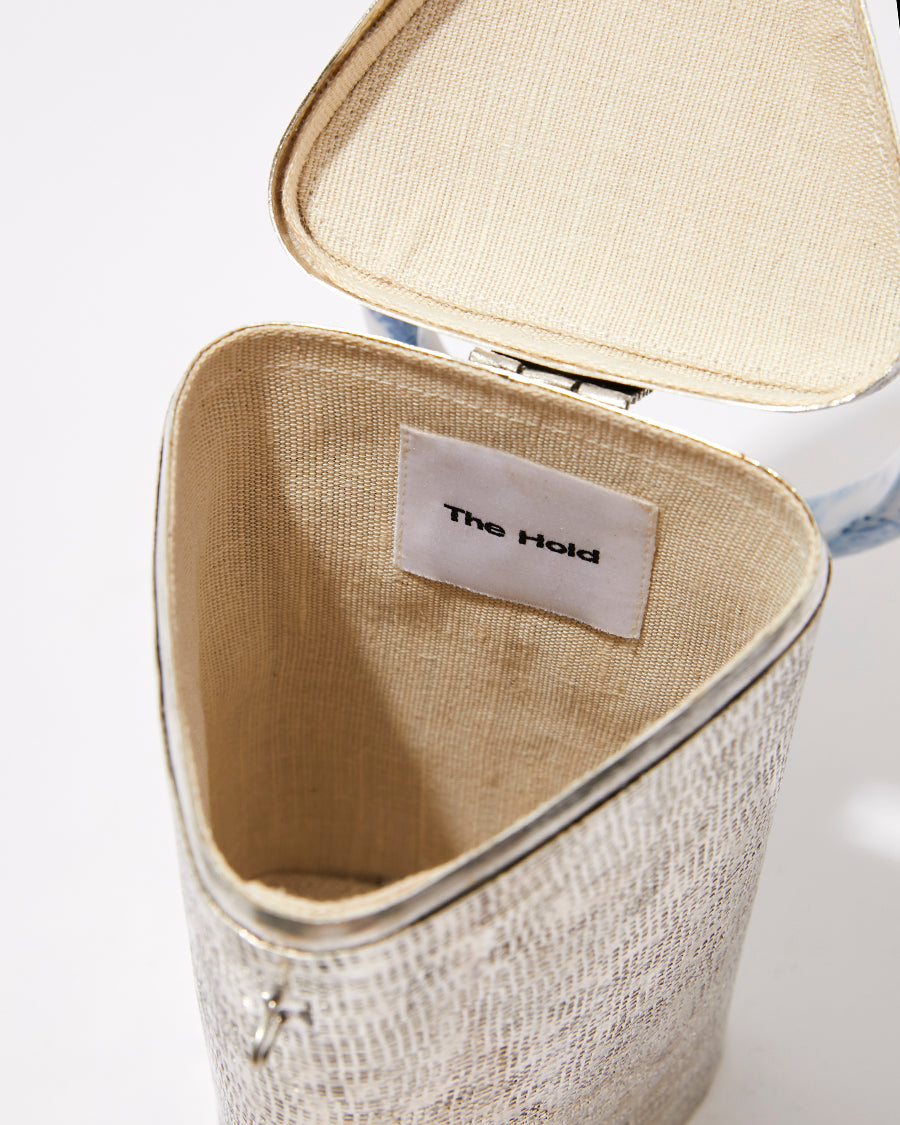 Open top view of the brass handbag showing the natural jute lining and interior space designed to fit an iPhone Plus and essentials