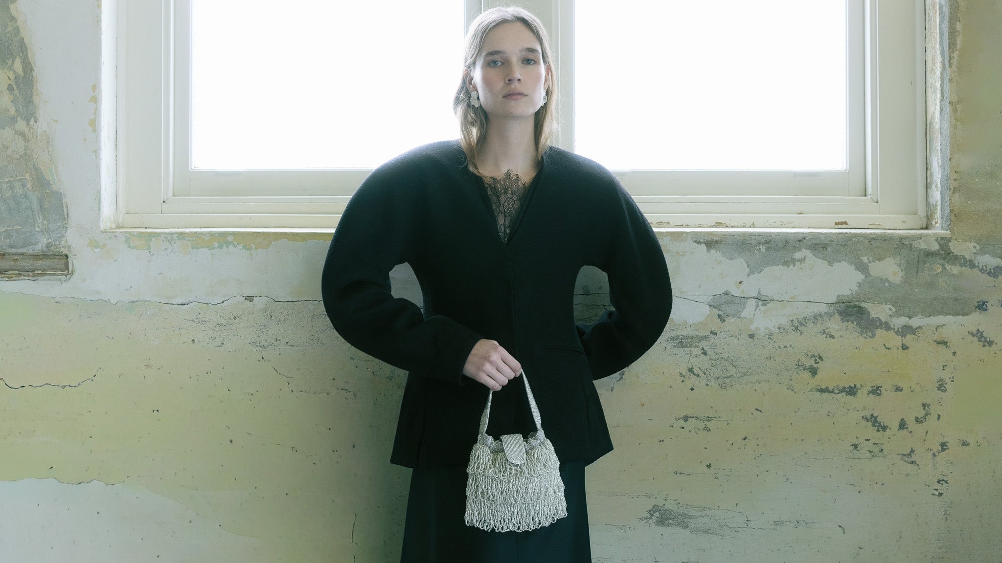 Model carrying a silver beaded tassel bag with layered fringe, styled with a black dress.