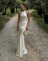 Women in a white satin bridal gown carrying the champagne shell-shaped beaded clutch, perfect for bridal celebrations.