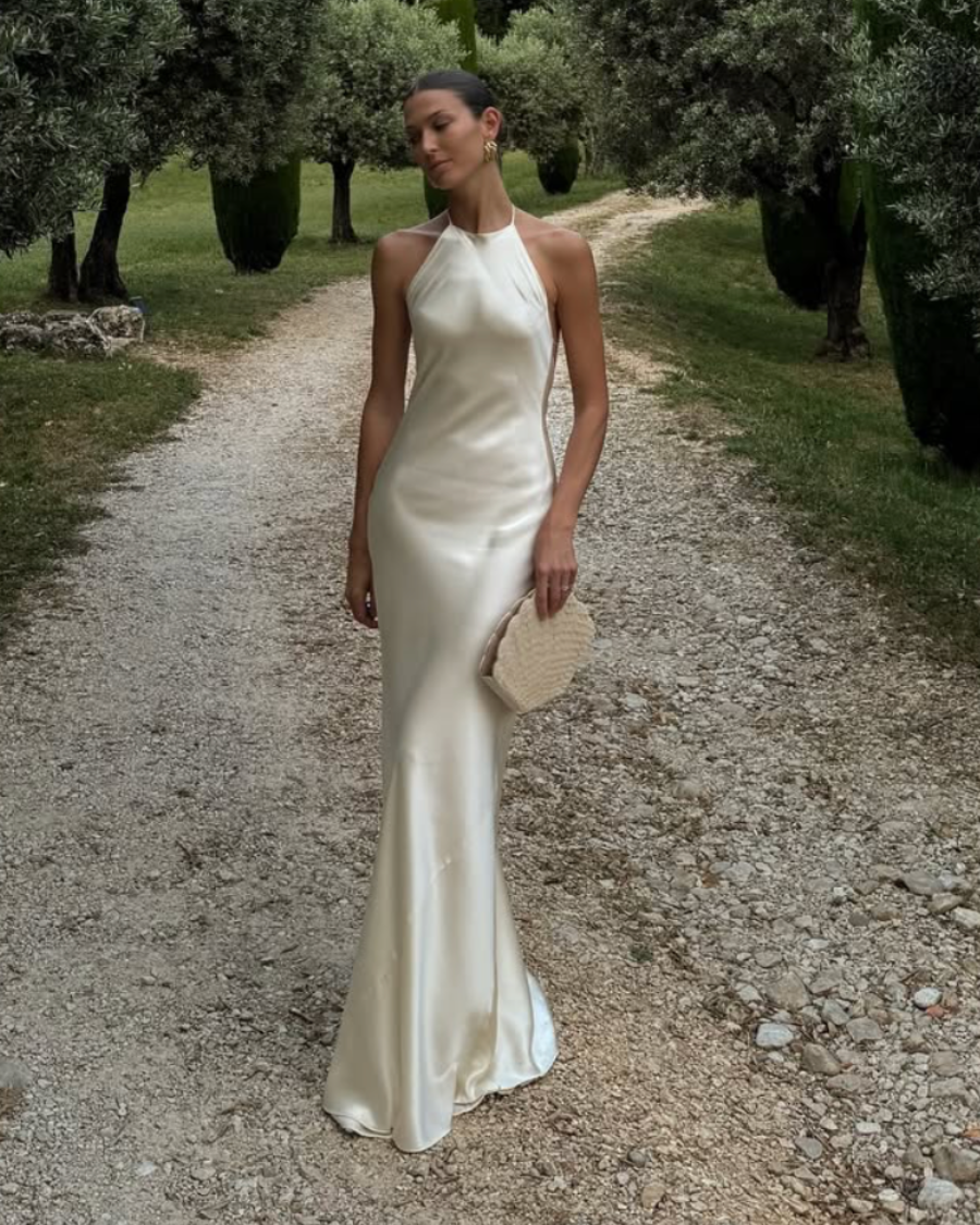 Women in a white satin bridal gown carrying the champagne shell-shaped beaded clutch, perfect for bridal celebrations.