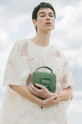 Model holding the jade green Uncovered Layers beaded bag, showcasing its vibrant colour and hand-dyed glass bead texture.
