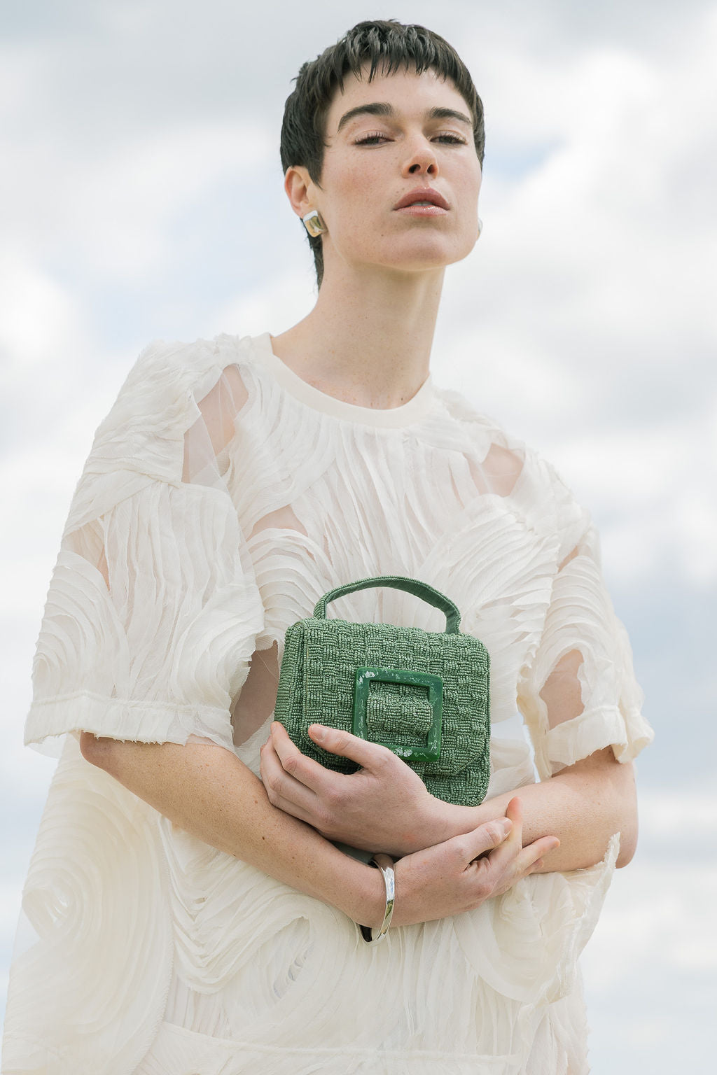 Model holding the jade green Uncovered Layers beaded bag, showcasing its vibrant colour and hand-dyed glass bead texture.