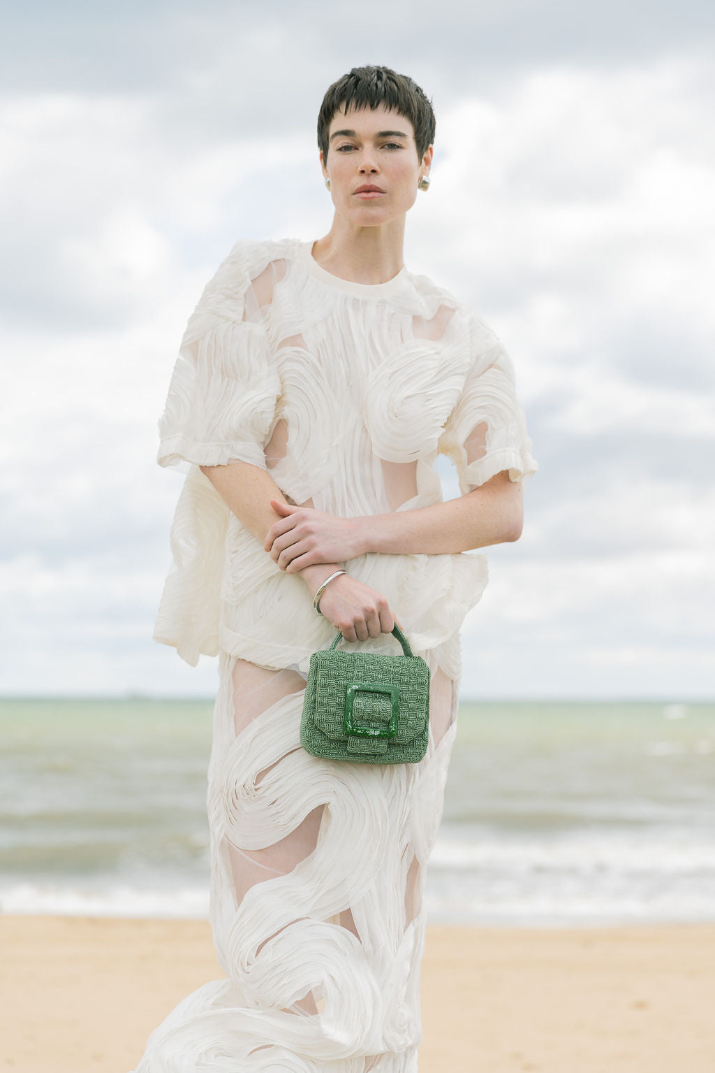 Model walking outdoors carrying the jade green Uncovered Layers bag, demonstrating its use as an elevated everyday accessory.