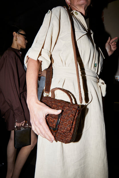 Candid lifestyle shot of the rich brown Uncovered Layers bag being worn as a crossbody, highlighting its wearable, everyday appeal.