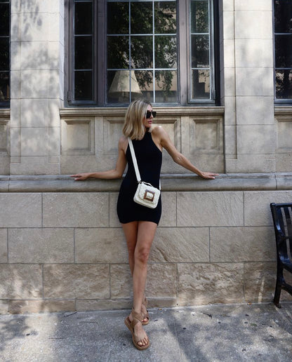 UCG styling the white Uncovered Layers bag as a crossbody over a black mini dress, highlighting its versatility as an elevated everyday bag.