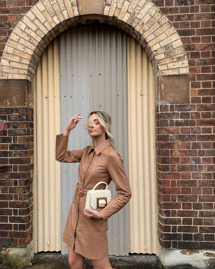 UCGl with the white Uncovered Layers bag in an urban archway, emphasising its modern, sculptural design.