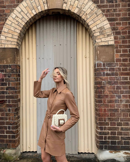 UCGl with the white Uncovered Layers bag in an urban archway, emphasising its modern, sculptural design.