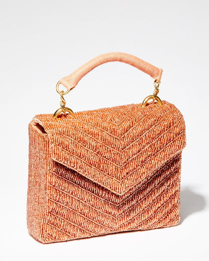 Three-quarter studio view of the artisan-made Waves Never Cease peach beaded handbag with a hand-sewn chevron pattern and jute handle.