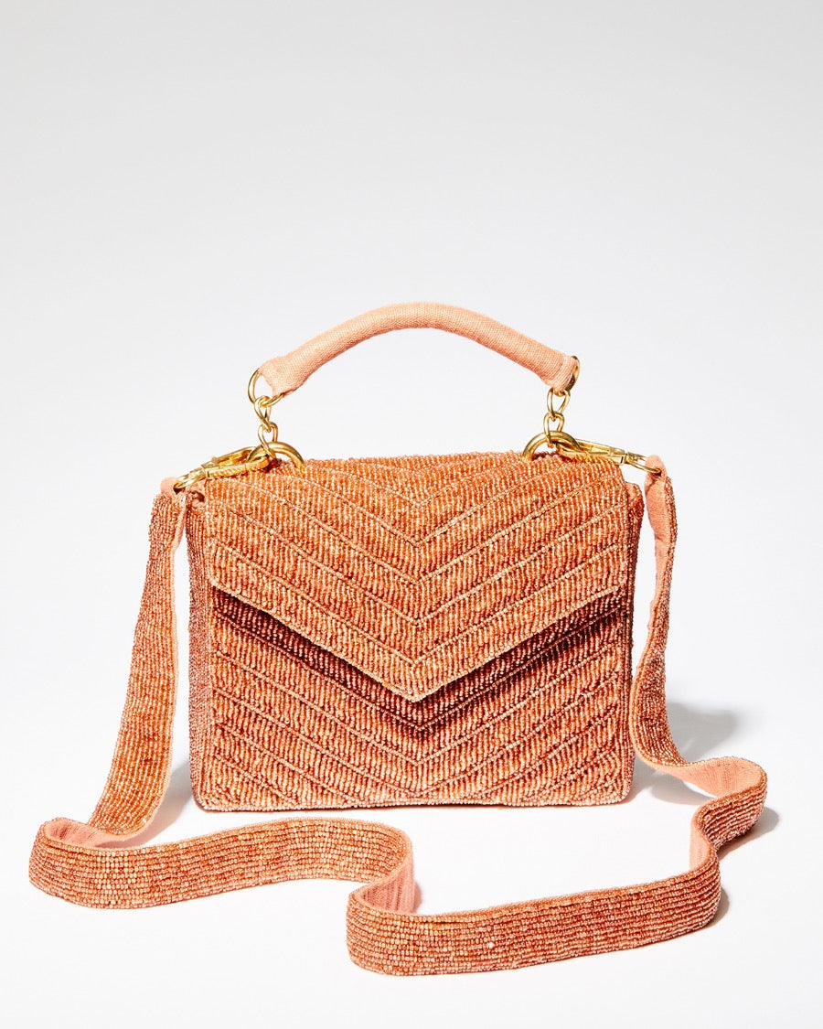 Front view of the handcrafted peach beaded bag highlighting the downward chevron pattern and magnetic closure flap.