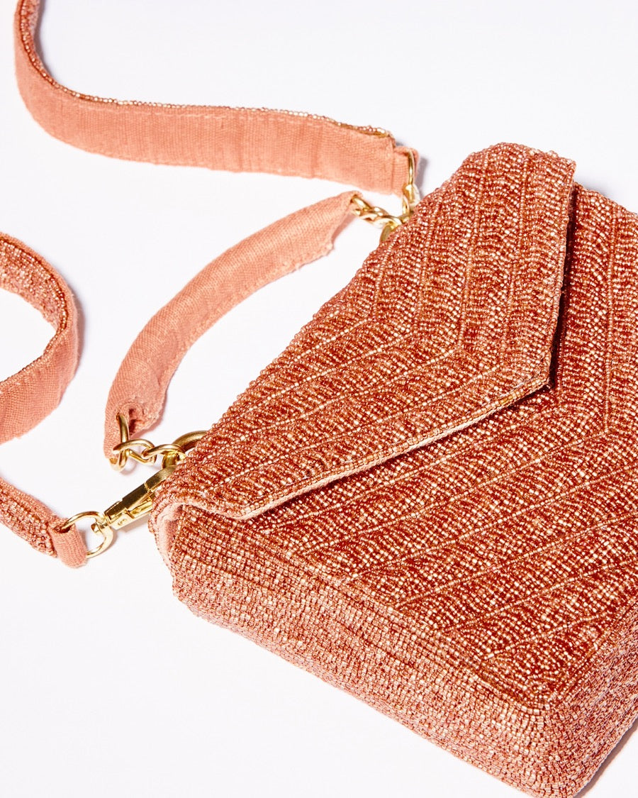 Flat studio shot of the Waves Never Cease bag in apricot with its 110cm removable beaded crossbody strap fully displayed.