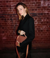 UCG in a black blazer holding the peach beaded bag by its handle, demonstrating its use as an elegant evening handbag.
