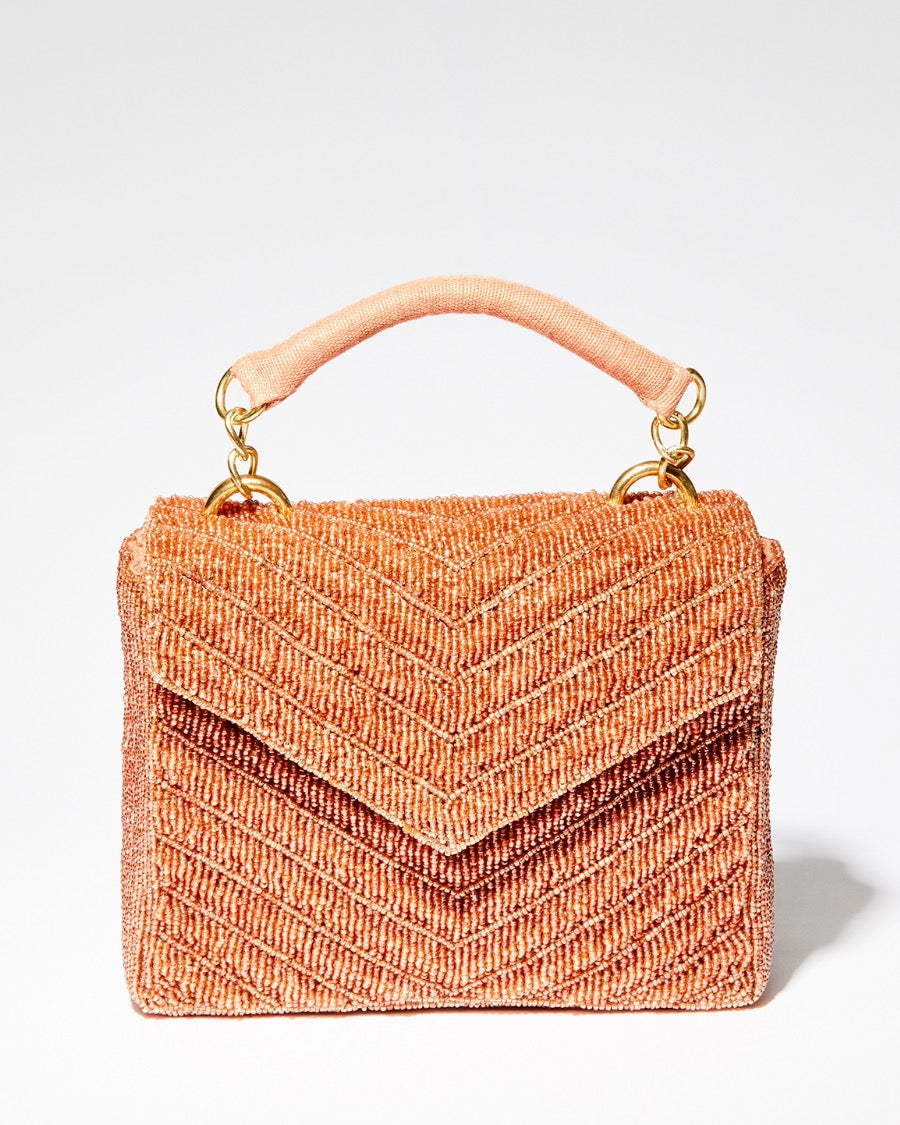 A close-up shot of the peach beaded bag being held by the jute top handle, emphasizing the hand-dyed glass beads and artisan detail.