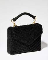 Three-quarter view of the artisan-made Waves Never Cease black beaded handbag featuring a hand-sewn downward chevron pattern and jute handle.