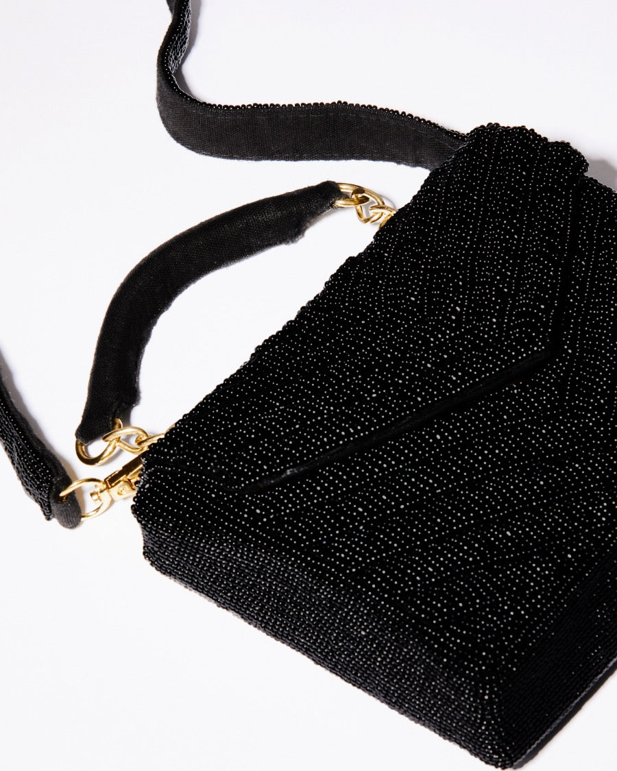 Close-up detail of the hand-dyed black glass beads and gold chain hardware on the Waves Never Cease event bag.