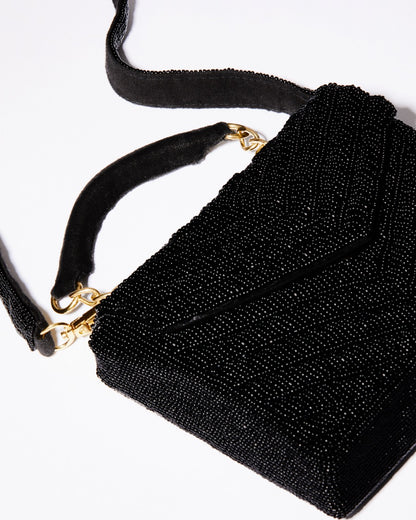 Close-up detail of the hand-dyed black glass beads and gold chain hardware on the Waves Never Cease event bag.