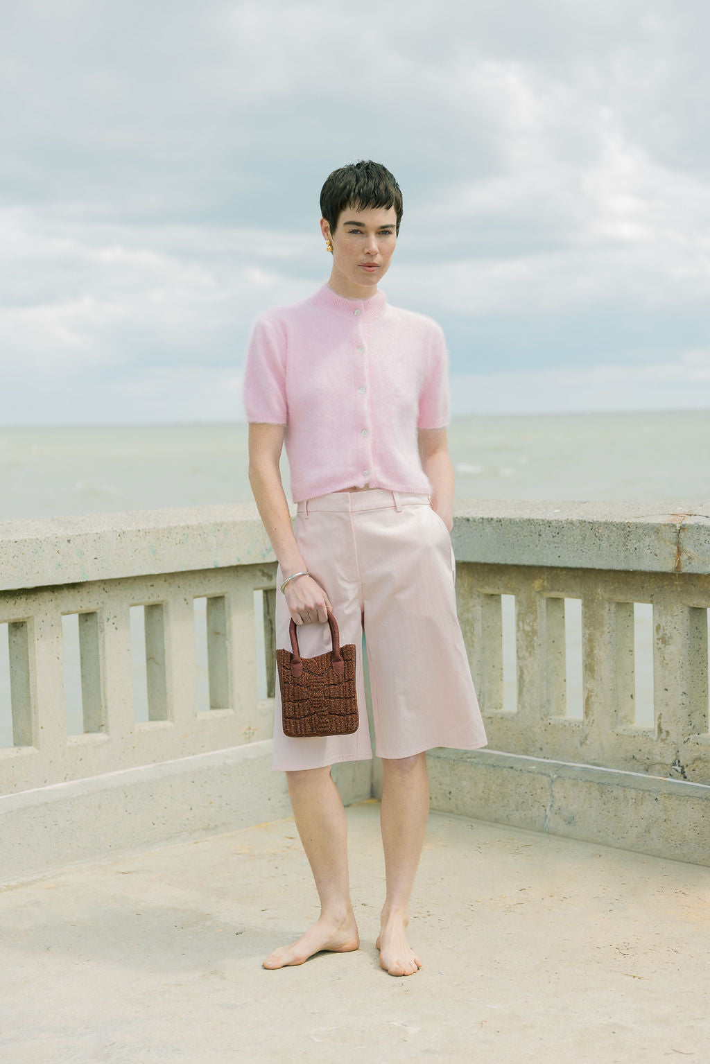 Model styling the artisan-made burgundy beaded bag with a casual outdoor outfit, showcasing a minimalist fashion trend.