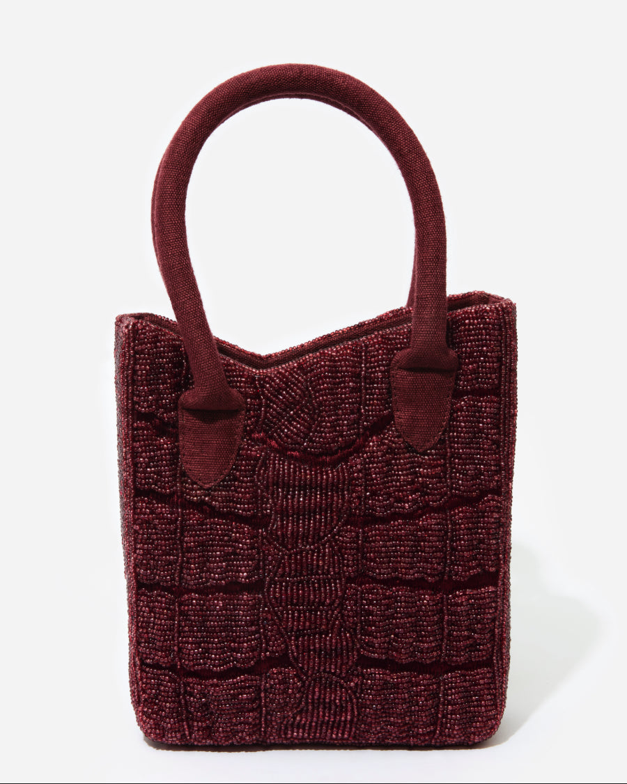 A straight-on studio shot of the artisan-made Wonder Before Why beaded bag, showing the symmetry of the handcrafted beadwork.