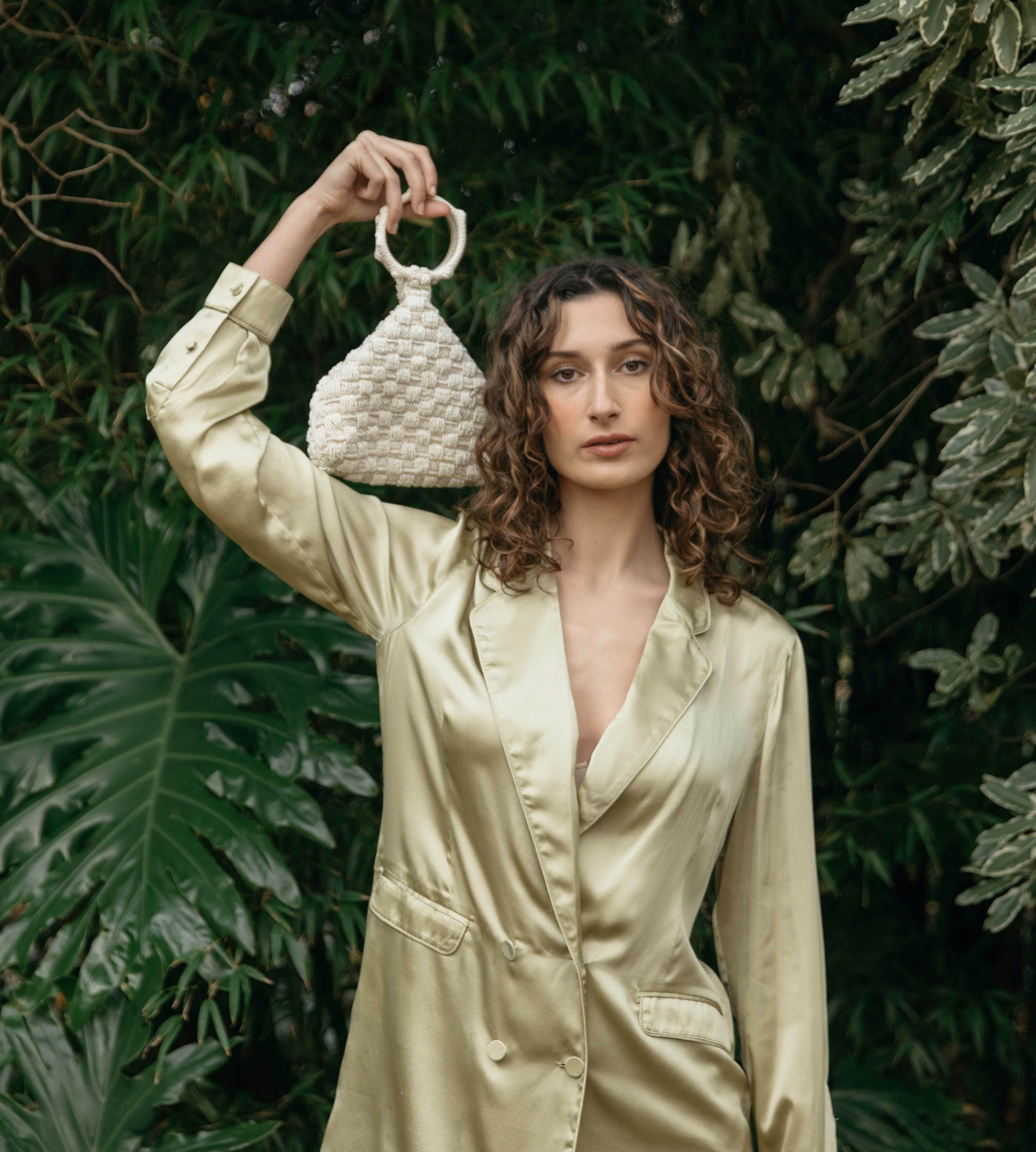 Intimate Exchange ivory beaded bag styled against silk suit in the gardens 