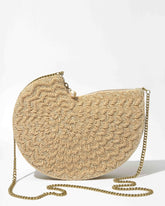 Three-quarter studio view of the Beyond Us champagne beaded clutch featuring a sculptural half-moon silhouette and detachable gold chain strap.