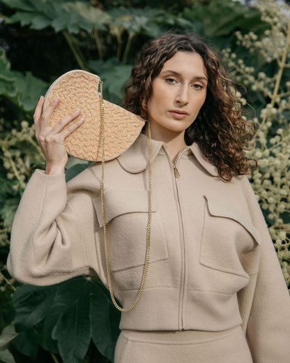 Model in a tan coordinated set holding the Beyond Us half-moon clutch, highlighting its intricate embossed beadwork for bridal celebrations