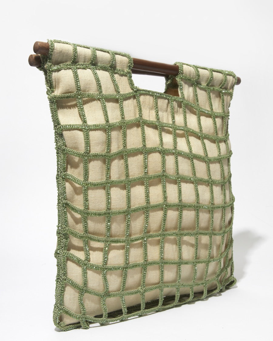 Three-quarter studio view of the sage green Entwined Tote, showcasing the intricate beaded crochet grid and dark wooden bar handles.