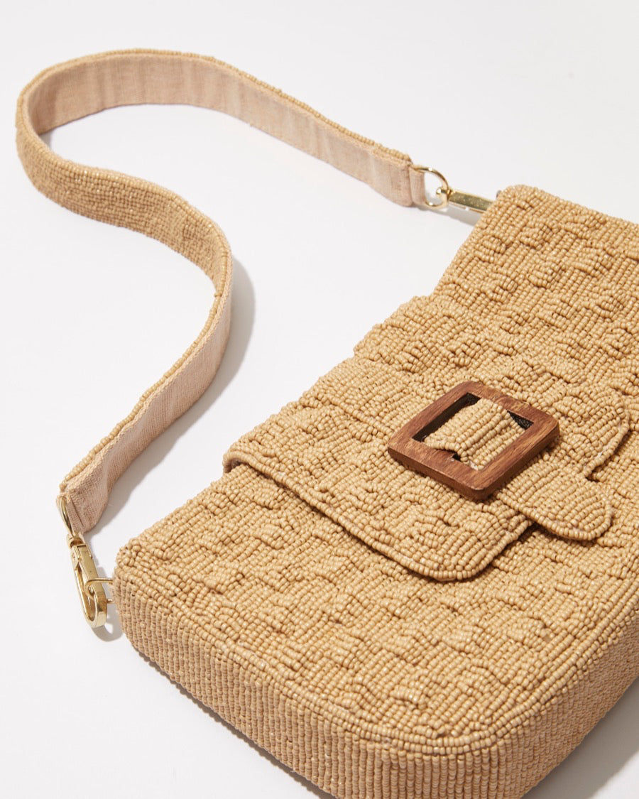 Close-up of the embossed woven beadwork and the natural wooden buckle interwoven into the top fold of the Familiar Way bag