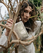 Candid portrait of a model holding the Modern World bag, showcasing the hand-beaten metal technique that makes each piece unique.