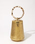 Front studio view of the Perception of Time gold brass bag, featuring a tapered hand-beaten metal body and a circular tortoiseshell resin handle.