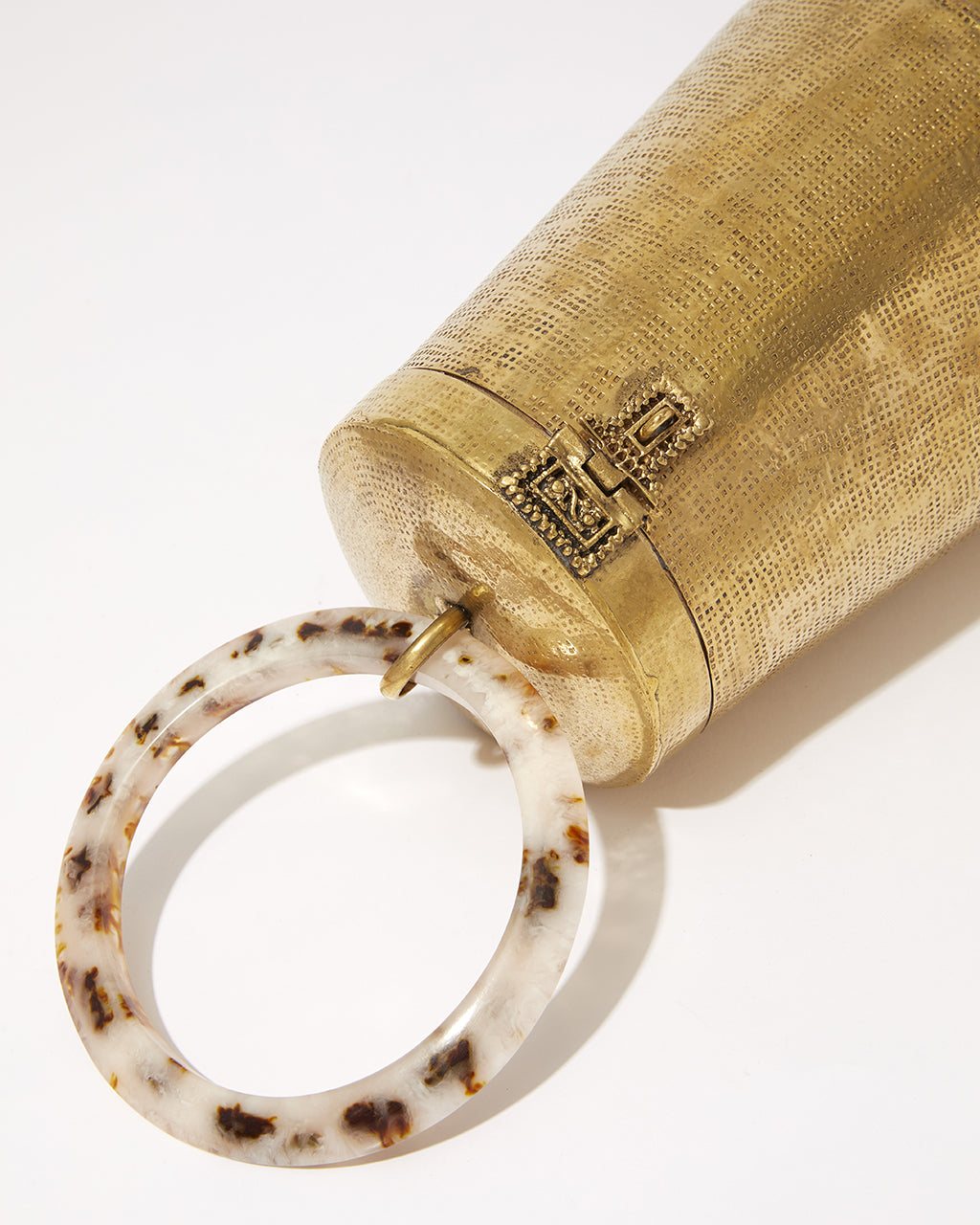 Close-up of the intricate metal clasp and the hand-beaten texture of the gold brass body on the Perception of Time bag.