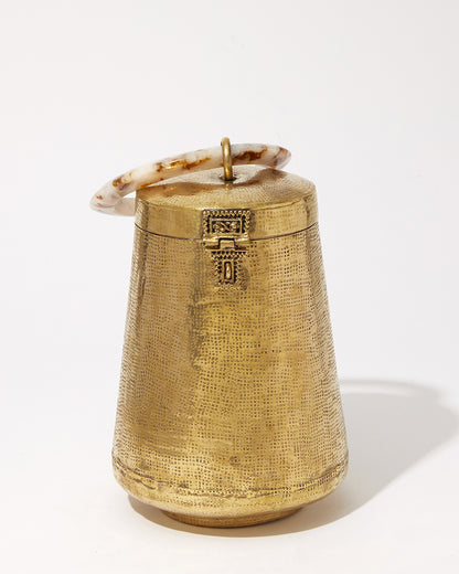 Top-down view of the Perception of Time bag showing the connection between the polished resin handle and the textured brass body.