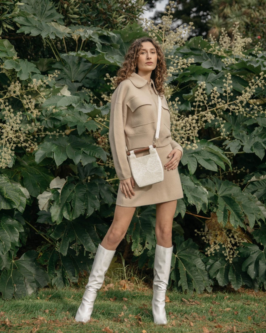 Model in a beige outfit carrying the white Reach for Words bag as a crossbody, showcasing the long detachable beaded strap.